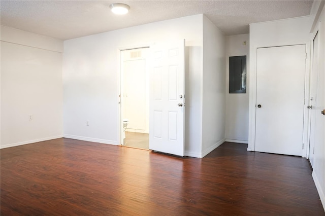 empty room featuring a textured ceiling, dark hardwood / wood-style floors, and electric panel