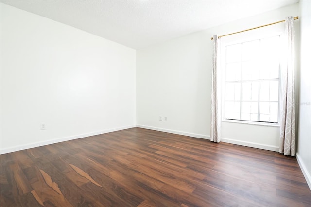 empty room featuring a textured ceiling and dark hardwood / wood-style flooring