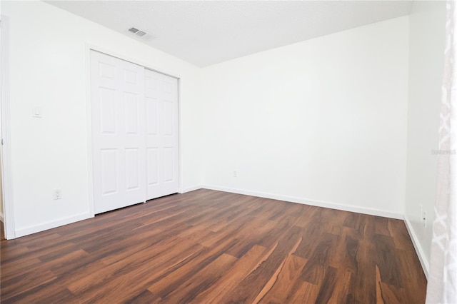 unfurnished bedroom featuring a closet and dark hardwood / wood-style flooring