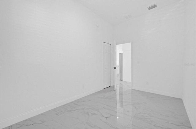 unfurnished room with marble finish floor, visible vents, and baseboards