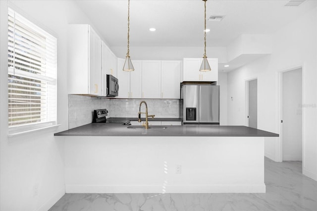 kitchen with stainless steel appliances, tasteful backsplash, white cabinetry, a sink, and a peninsula