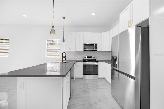 kitchen featuring marble finish floor, stainless steel appliances, backsplash, a sink, and a peninsula