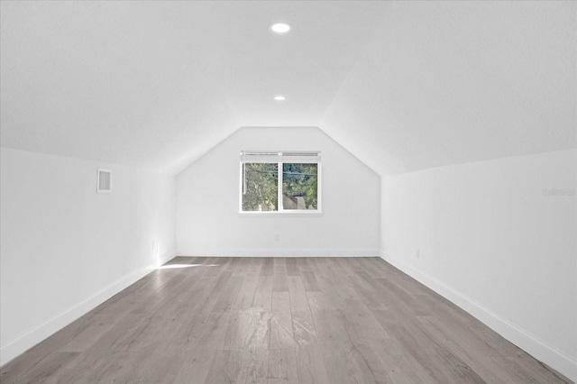 bonus room with lofted ceiling, wood finished floors, visible vents, and baseboards