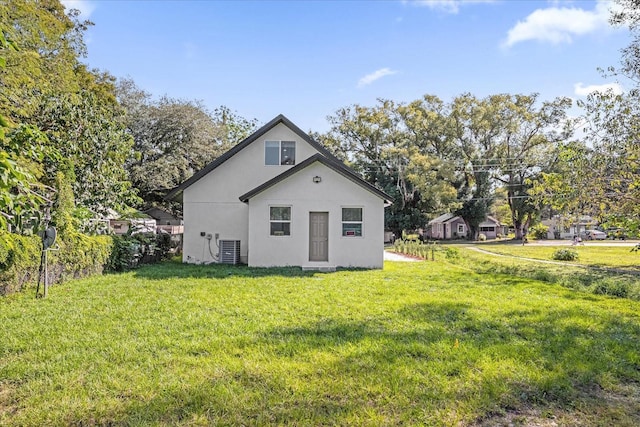 rear view of property with central AC, a lawn, and stucco siding