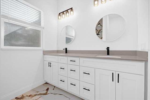 bathroom featuring marble finish floor, double vanity, a sink, and baseboards