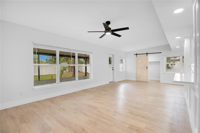 unfurnished living room featuring a barn door, plenty of natural light, and light wood-type flooring