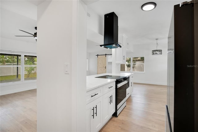 kitchen with a barn door, a healthy amount of sunlight, white cabinets, and exhaust hood