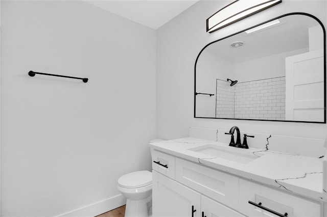 bathroom featuring toilet, vanity, hardwood / wood-style flooring, and a tile shower