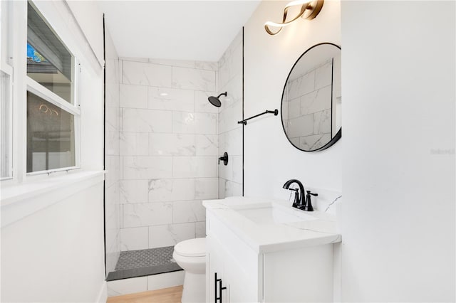 bathroom with toilet, vanity, hardwood / wood-style flooring, and tiled shower