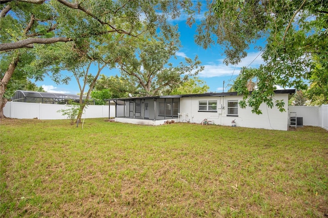 rear view of property with cooling unit, a sunroom, and a yard