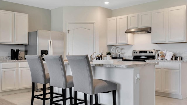 kitchen with stainless steel appliances, a kitchen island, light tile patterned floors, a kitchen breakfast bar, and white cabinets