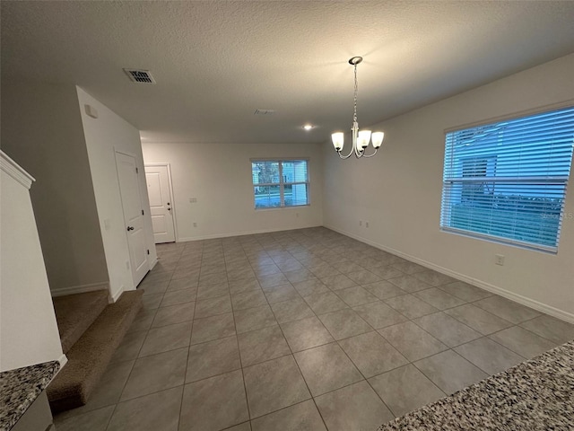 unfurnished dining area featuring light tile patterned flooring, a textured ceiling, and an inviting chandelier