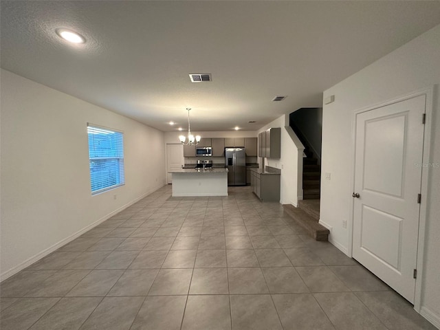 kitchen featuring stainless steel appliances, light tile patterned floors, an inviting chandelier, a kitchen island, and hanging light fixtures