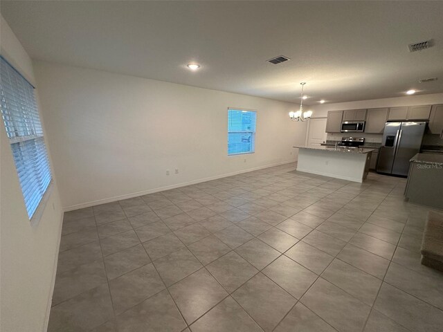 unfurnished living room featuring light tile patterned flooring and an inviting chandelier