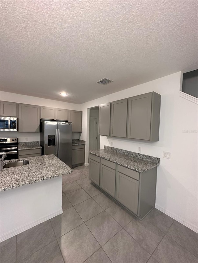 kitchen featuring a textured ceiling, gray cabinets, sink, and stainless steel appliances