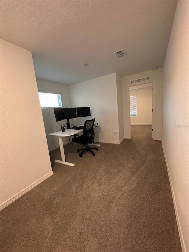 unfurnished office with dark carpet and a textured ceiling