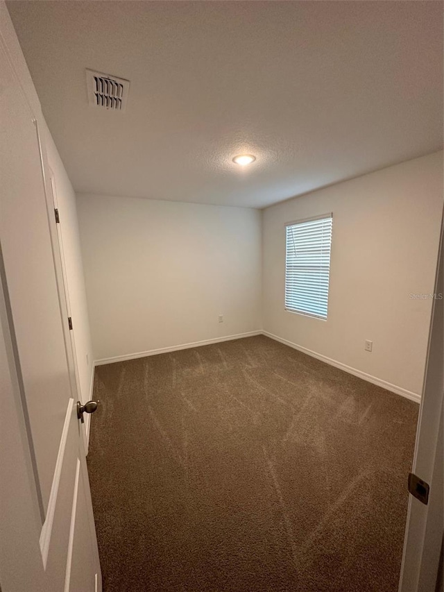 spare room with dark carpet and a textured ceiling