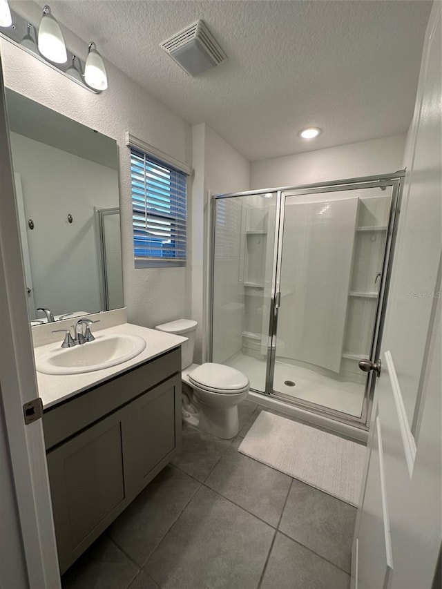 bathroom with tile patterned flooring, toilet, an enclosed shower, and a textured ceiling