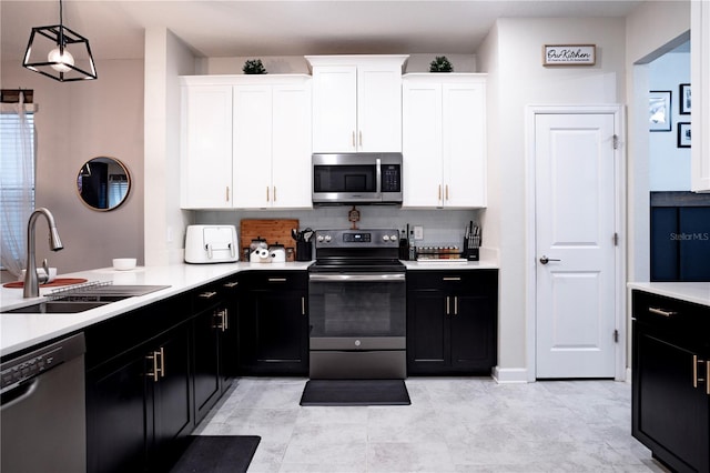 kitchen featuring white cabinetry, sink, appliances with stainless steel finishes, hanging light fixtures, and decorative backsplash