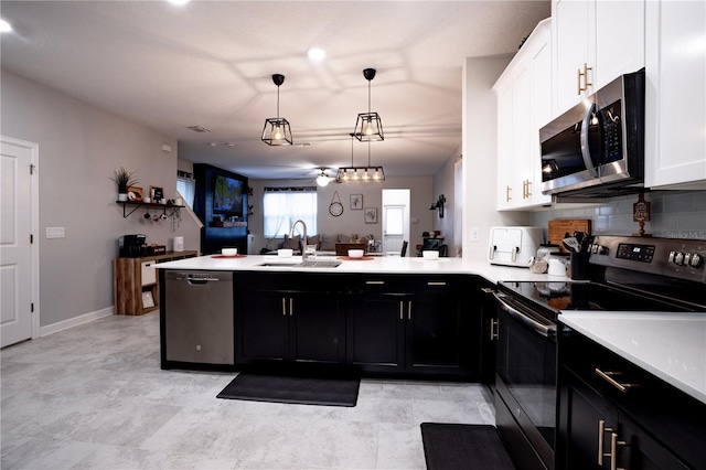 kitchen with appliances with stainless steel finishes, decorative light fixtures, sink, white cabinets, and kitchen peninsula