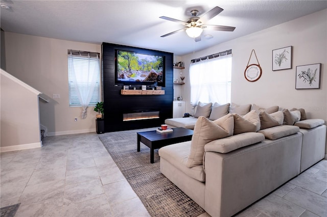 living room with ceiling fan, plenty of natural light, a large fireplace, and a textured ceiling