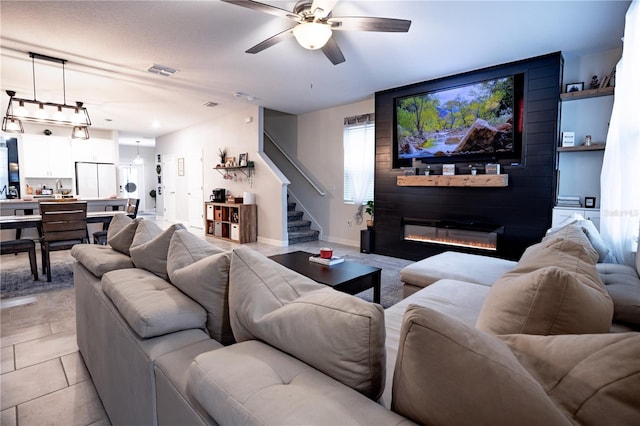 living room featuring a fireplace, ceiling fan, and light tile patterned floors