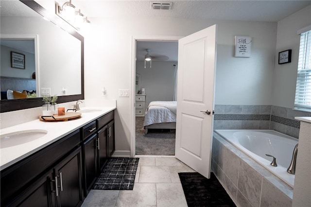 bathroom featuring tiled bath, vanity, a textured ceiling, tile patterned flooring, and ceiling fan