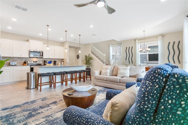 tiled living room featuring ceiling fan with notable chandelier