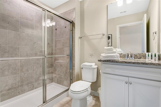 bathroom featuring a shower with door, vanity, and toilet