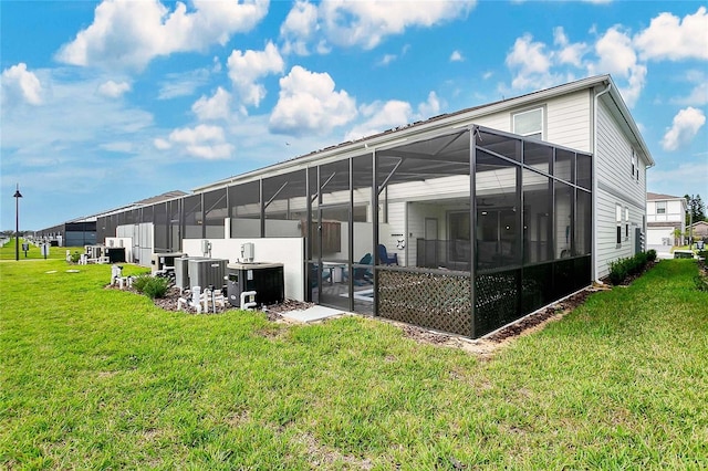 back of property with glass enclosure and a lawn