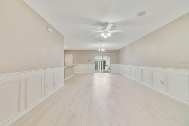 unfurnished room featuring ceiling fan with notable chandelier and light hardwood / wood-style flooring