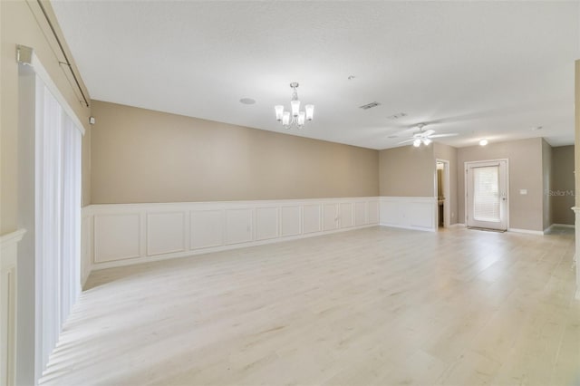 empty room featuring ceiling fan with notable chandelier, light hardwood / wood-style floors, and a textured ceiling