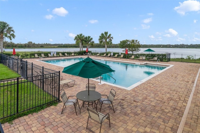 view of pool with a water view, a lawn, and a patio area