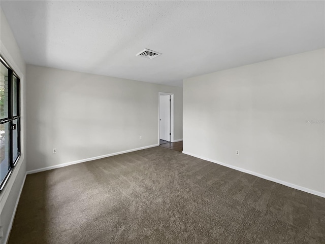 spare room featuring dark colored carpet