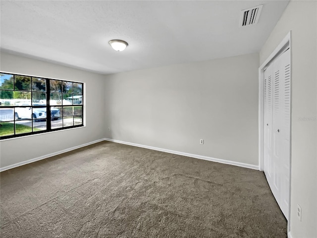 unfurnished bedroom featuring a closet and dark carpet