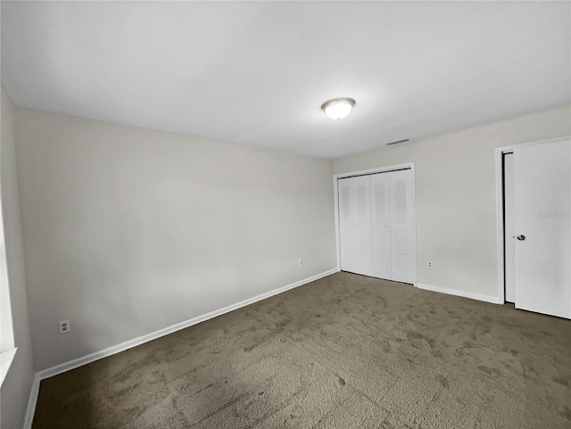 unfurnished bedroom with a closet and dark carpet