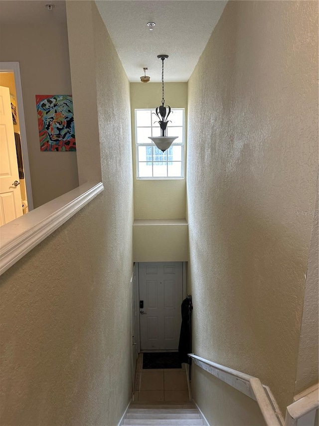 stairway with tile patterned flooring and a textured ceiling