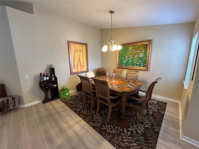 dining area featuring wood-type flooring, an inviting chandelier, and vaulted ceiling