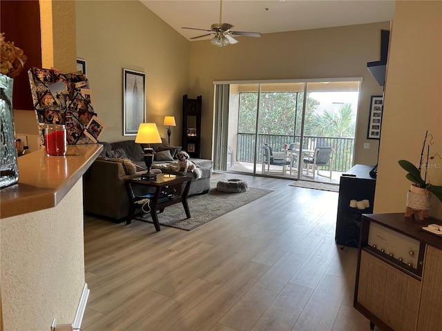 living room featuring light hardwood / wood-style floors, ceiling fan, and high vaulted ceiling