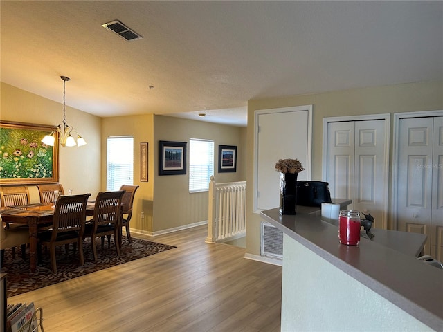 dining room featuring wood-type flooring, a textured ceiling, and an inviting chandelier