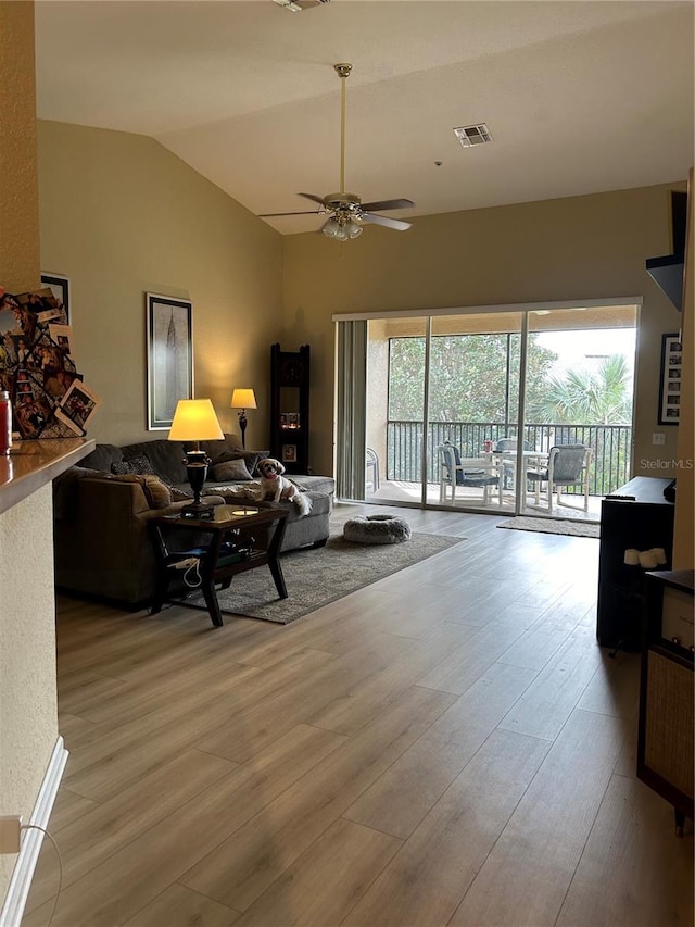 living room with ceiling fan, light wood-type flooring, and vaulted ceiling