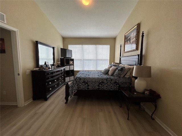 bedroom with hardwood / wood-style flooring and lofted ceiling