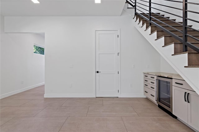 interior space with beverage cooler, light tile patterned floors, and white cabinets