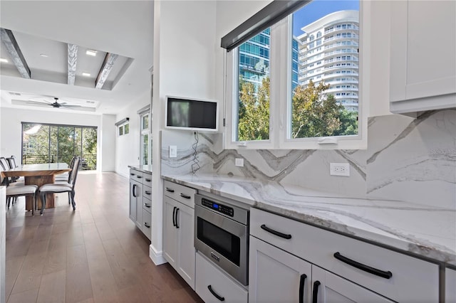 kitchen featuring tasteful backsplash, light stone countertops, hardwood / wood-style flooring, beamed ceiling, and ceiling fan