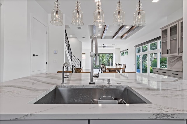 kitchen featuring hanging light fixtures, ceiling fan, and light stone counters