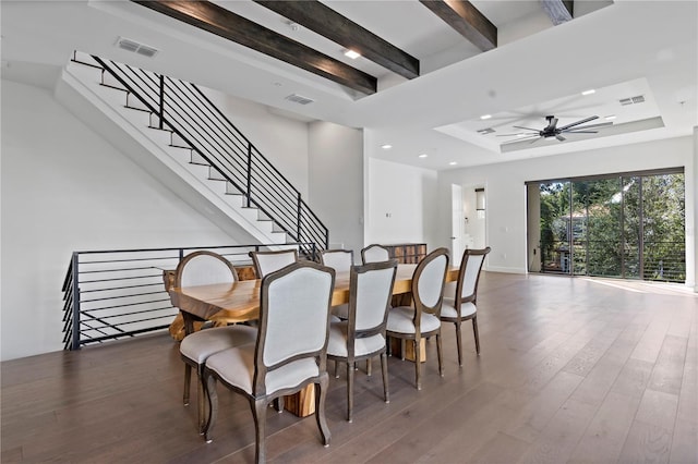 dining space with dark wood-type flooring, beamed ceiling, a tray ceiling, and ceiling fan