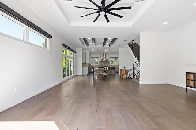 unfurnished living room with dark wood-type flooring, a tray ceiling, and ceiling fan