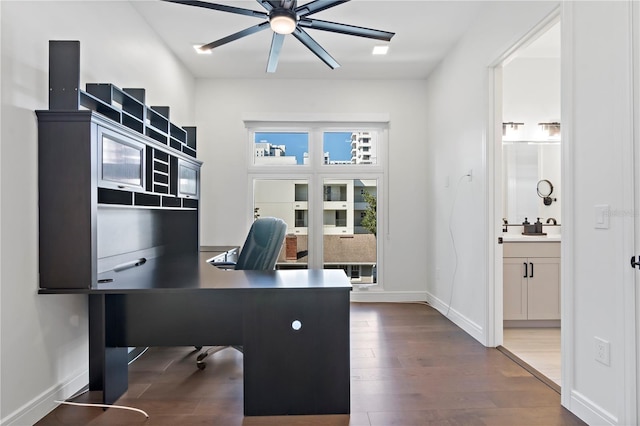 home office with dark wood-type flooring, ceiling fan, and sink