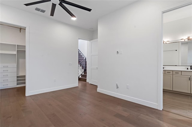 unfurnished bedroom featuring hardwood / wood-style flooring, ceiling fan, ensuite bath, and a spacious closet