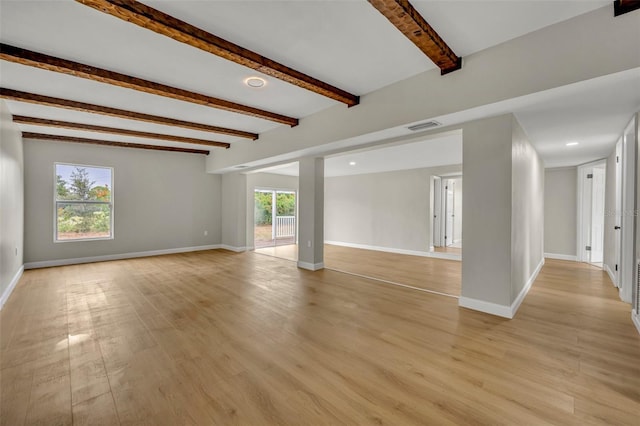 spare room with beamed ceiling and light hardwood / wood-style flooring